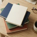 Stack of finance books with reading glasses and coffee, representing a personal finance reading list